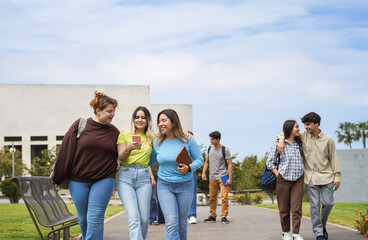 Young group of friends having fun outside with school building on background - School and campus lifestyle concept - Focus on left girls faces