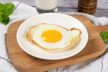 fried egg in a white plate on table.