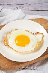 fried egg in a white plate on table.