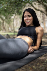 Young woman wearing sportswear, exercising in the park surrounded by nature, healthy and active lifestyle, fitness life