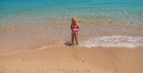 Child playing with sand on the beach at sea. Selective focus.