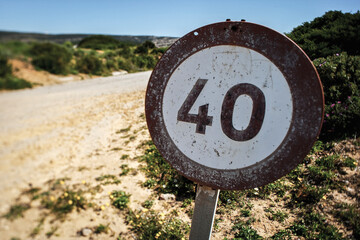 A weather-beaten speed limit sign indicating 40 km stands along a dusty path in an arid desert landscape, reflecting the passage of time and the harsh environment.