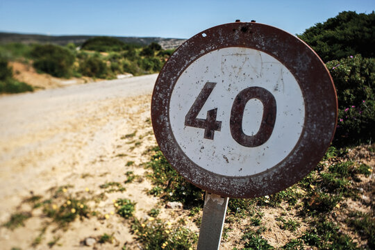 A weather-beaten speed limit sign indicating 40 km stands along a dusty path in an arid desert landscape, reflecting the passage of time and the harsh environment.