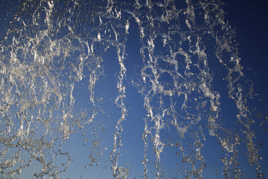 A mesmerizing capture of water splashing dramatically against a clear blue sky, showcasing the dynamic and fluid beauty of nature in motion.