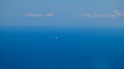 Ship in the endless sea. Aerial view of the ocean surface and a cargo ship in the center.