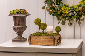 Decorative tabletop arrangement featuring moss-covered trees and a candle in a rustic wooden box...