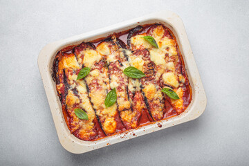 Eggplant parmigiana di melanzane freshly baked and decorated with basil leaves, resting in a baking...
