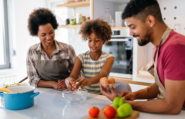 Happy black family in the kitchen having fun and cooking together. Healthy food at home.