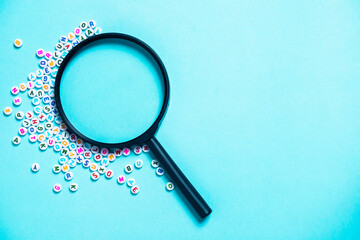 English letters scattered on blue background. Concept of thinking development, grammar. Magnifying...