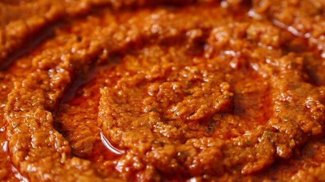 Homemade tomato and basil red pesto sauce texture circle rotation close up