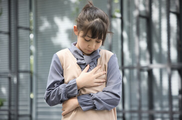 ill Asian little female child having heart sickness, chest pain, acid reflux or gerd symptoms,...