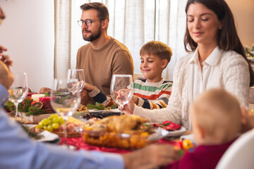 Family praying before Christmas dinner at home