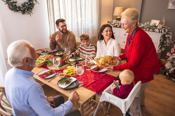 Senior woman bringing food to the table for family Christmas dinner