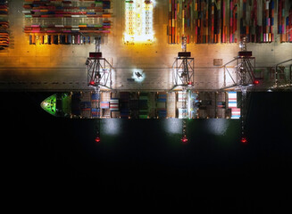 Aerial view of Industrial shipping port. View from drone. Loading containers on the ship, cranes load containers. Night shooting.