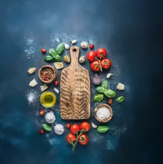 Tableau sur plexiglas Cuisine A wooden cutting board sits in the center of a blue surface surrounded by ingredients.  © joeycheung