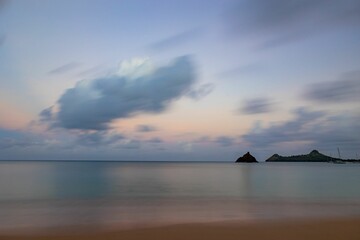 Serene seascape at sunset with distant islands and colorful sky.