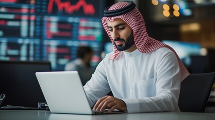 Young professional in traditional attire analyzing stock market trends on a laptop in a modern office environment during the day