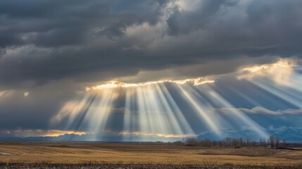 Sunlight through storm clouds, creating dramatic beams across the landscape