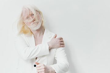 Portrait of a model with white hair in a white suit, showcasing modern fashion against a minimalist...