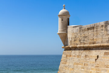 Watchtower of a fort overlooking the Atlantic Ocean with a blue sky. Sesimbra Portugal.