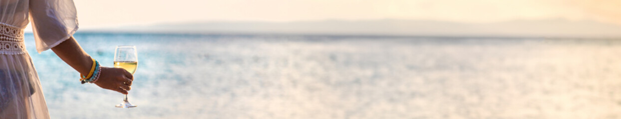 Woman with a glass of wine at the sea. Selective focus.