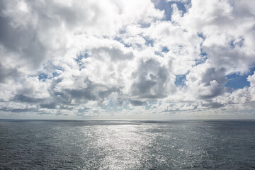Bewolkte lucht met spiegelend zonlicht op de golven van de zee