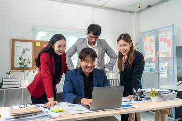 A group of people are gathered around a laptop in a conference room