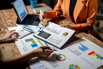 Businesswomen analyzing financial charts and using calculator in a meeting