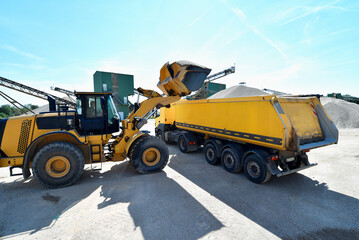 Wheel loader loads a truck with sand in a gravel pit