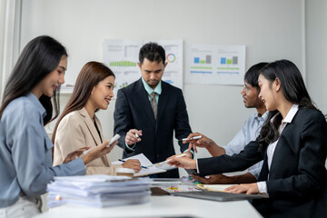 A group of people are sitting around a table with papers and a laptop