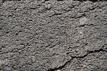 This image shows a close-up view of cracked concrete with a rough texture. The image can be used for backgrounds, textures, or design elements.
