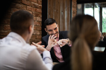 In a casual cafe setting, a group of young professionals engage in a lively business discussion, exchanging ideas and strategies.