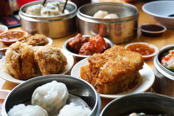 Traditional Chinese dim sum in metal bowl on wooden table. A lot of different kinds of food and...
