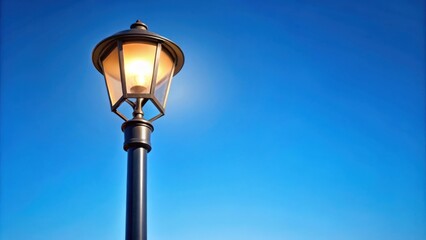Modern street lamp shining against a clear blue sky