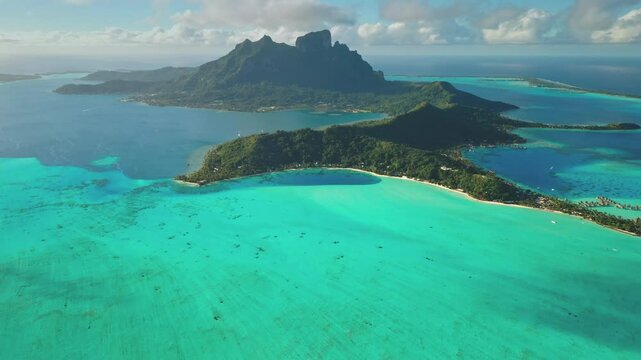 Bora Bora island beauty and tranquility tropical paradise. Turquoise coral reef lagoon, towering green mountain. Remote wild nature exotic summer vacation travel background. Drone aerial panorama shot