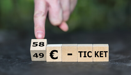 Hand dreht Würfel und ändert den Ausdruck '49 EUR Ticket' in '58 EUR Ticket'. Symbol für die...