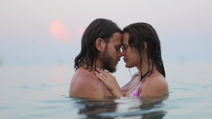 young couple in love in the sea hugging kissing swimming long-haired people