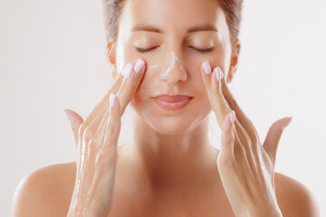 woman washing her face with special skin care product in the morning close-up, facial skin cleansing