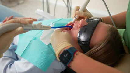 Close up Woman Dentist and Assistant Uses Modern Equipment to Treat Teeth on Female Patient in Dental Clinic. Medicine and Health Concept. Treatment Toothache. Slow Motion.