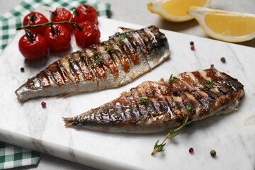 Board with delicious grilled mackerel, tomatoes and spices on table, closeup