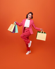 Cheerful happy businesswoman enjoying shopping, she is carrying shopping bags and jumping to get the latest offers at the shopping center.