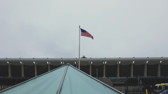 Flag close-up at Dulles Airport terminal, with the cloudy sky as a backdrop