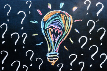 Colorful chalk drawing of a lightbulb and question marks. Brainstorming new ideas.