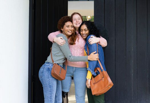 Hugging and smiling, three diverse women friends enjoying time together outdoors