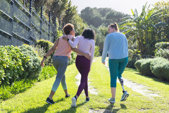 Walking together, diverse women friends enjoying outdoor stroll in lush garden