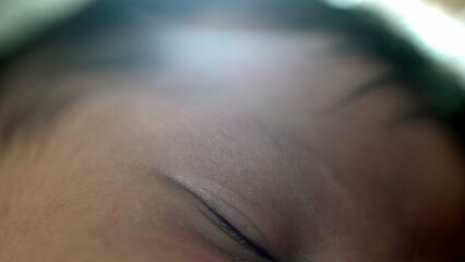 Artistic close-up of newborn’s closed eye while sleeping, with a dreamy light effect, emphasizing the innocence, peace, and delicate nature of a baby’s slumber