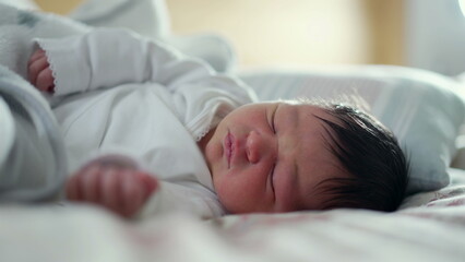 Newborn baby sleeping peacefully on a bed, face relaxed and calm, the tranquility and innocence of early life in a warm and cozy environment