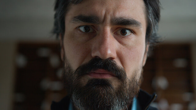 Moving shot portrait middle aged sad thoughtful Caucasian mature businessman employee psychologist man male with serious face expression sadness looks up eyes looking at camera indoors office cabinet