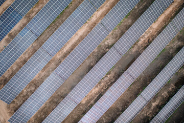 Aerial view of aligned rows of solar panels on the ground, showcasing a large-scale solar farm and renewable energy infrastructure.