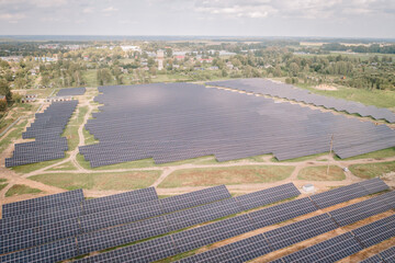 Aerial view of a vast solar farm with numerous solar panels generating renewable energy, set in a...